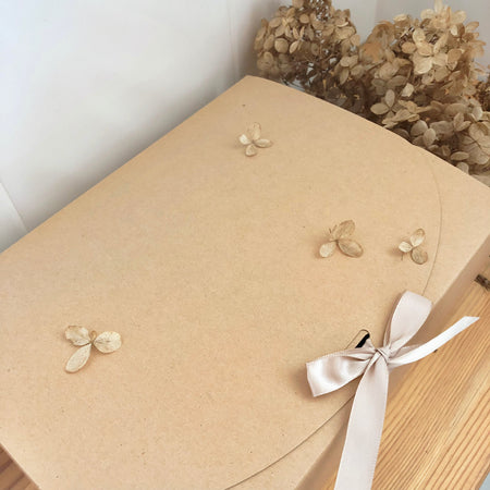 Beautiful Kraft color scallop gift box with beige ribbon and dried floral decor.