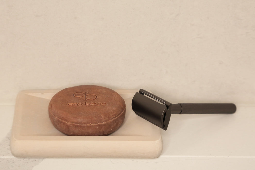 Matted black gold zinc alloy safety razor placed beside soap dish tray with side view, minimal background