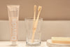 Eco-friendly bamboo toothbrush with Eco Beige engraved. Minimal style background with natural toothpaste and soap bar.