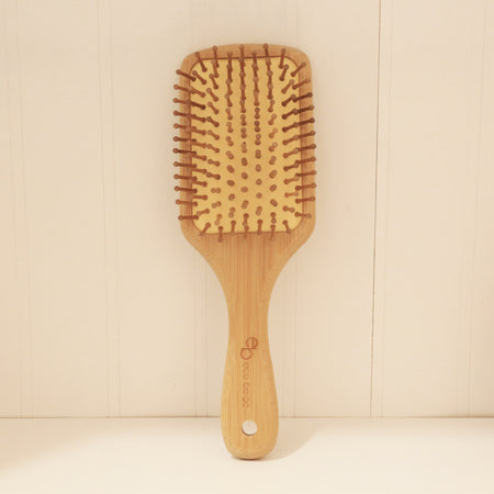 Rectangular cushioned bamboo hair brush with Eco Beige engraved on the handle. Standing straight against minimal background