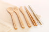 Detailed view of Eco Beige bamboo cutlery sets with logo engraved on bamboo spoon, fork, knife, chopsticks, and straws. White background with natural cotton mesh fabric layer.