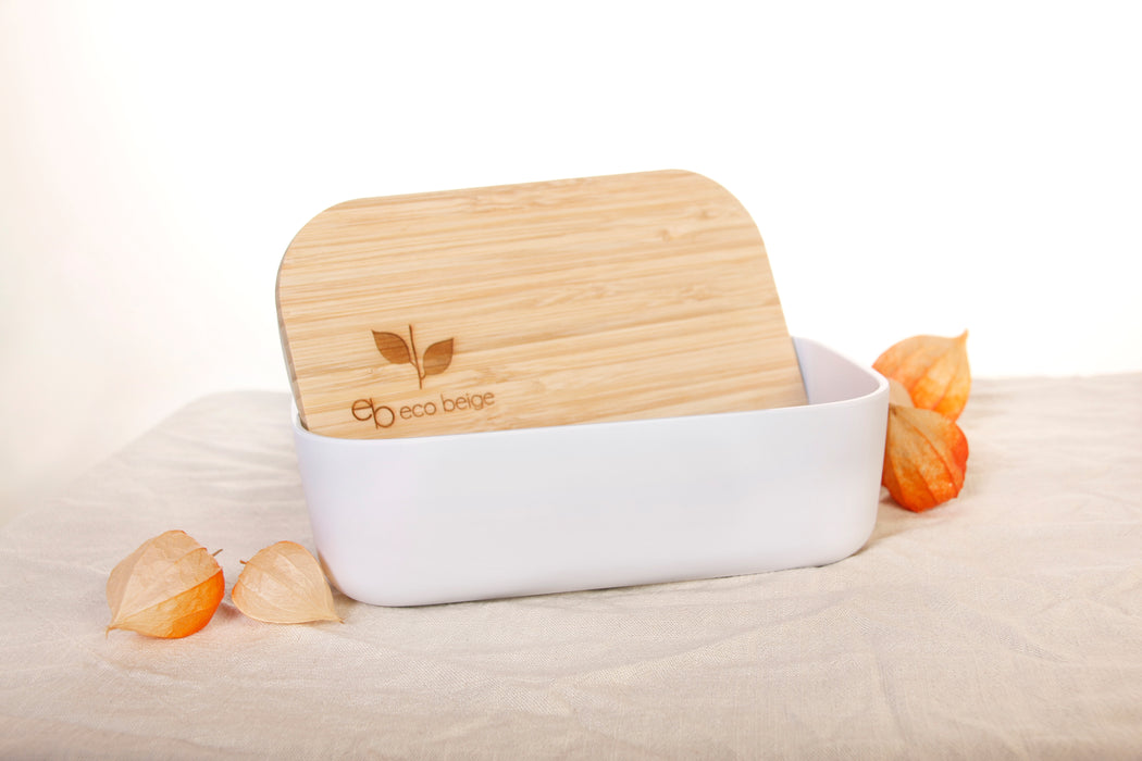 Eco Beige bamboo lunch box with engraved logo on the lid. Lunch box sit still view with lid inside the container. White container made with wheat fiber and bamboo fiber. White background with linen table cloth and red gooseberry flowers.