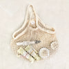Eco Beige cotton netted hand bag flat layed with cosmetic products inside, and light color stoned background.