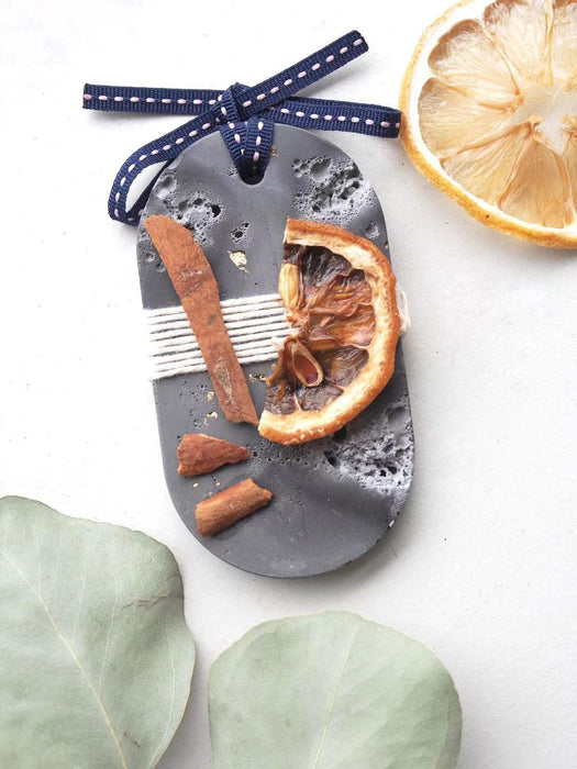 Musky Fall Plaster Freshener in grey concrete style and irregular texture. Decorated with dried citrus and cinnamon sticks. Long Ellipse shapes with ribbon tied at the top of tablet, used as a decorative diffuser.