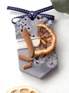 Musky Fall Plaster Freshener in grey concrete style and irregular texture. Decorated with dried citrus and cinnamon sticks. Long Hexagon shape with ribbon tied at the top of tablet, used as a decorative diffuser.