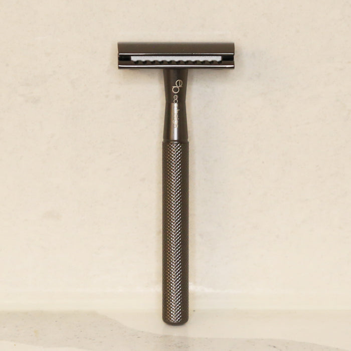 Matted black gold zinc alloy safety razor standing straight against minimal background.