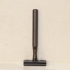 Matted black gold zinc alloy safety razor standing straight against minimal background.