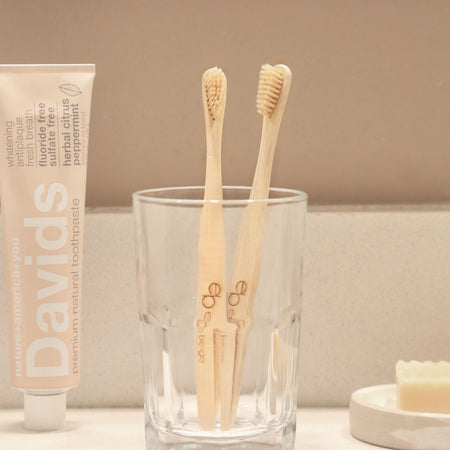 Eco-friendly bamboo toothbrush with Eco Beige engraved.  Minimal style background with natural toothpaste and soap bar.