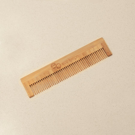 Eco Beige travel size bamboo comb with engraved logo and a cream background.