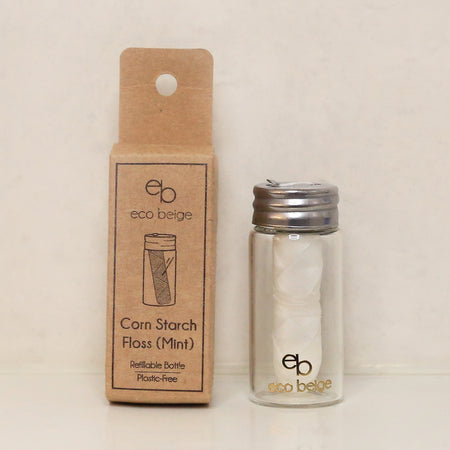 White corn starch dental floss in a glass bottle and metal lid with kraft box packaging.