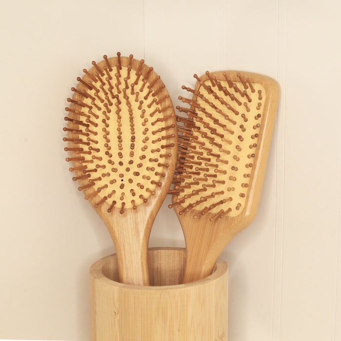 Oval and rectangular cushioned bamboo hair brushes in a bamboo case, and minimal background.