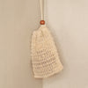 Natural sisal soap saver bag hanging on shower counter with soap inside.
