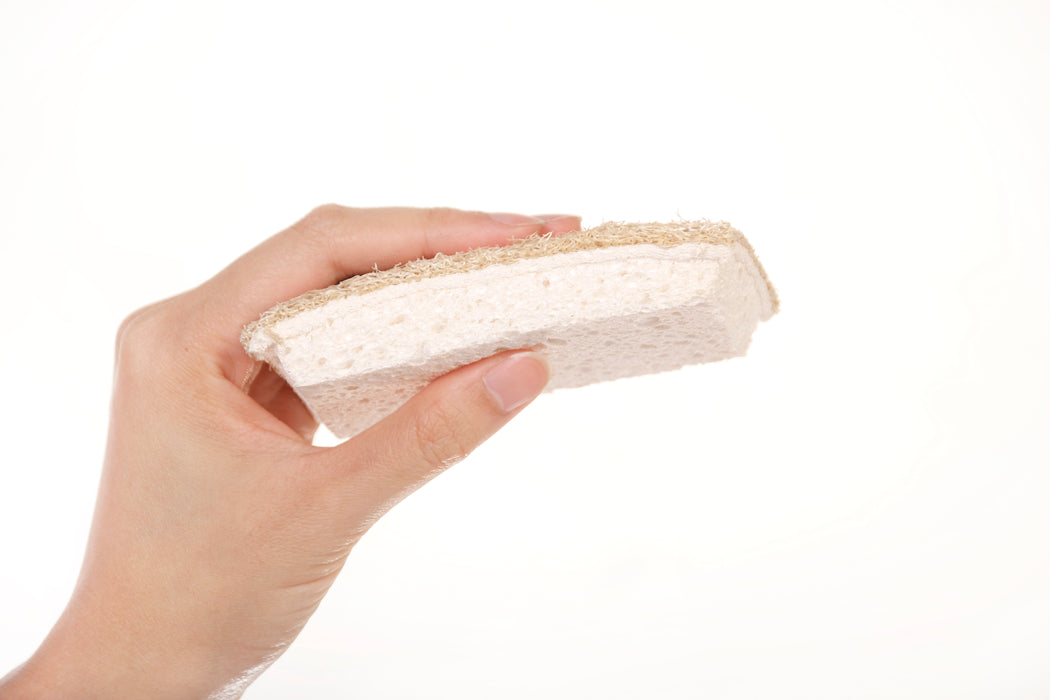 Eco Beige natural and fully compostable dish sponge made with wood cellulose fiber and loofah plant fiber. Hand held in side view.