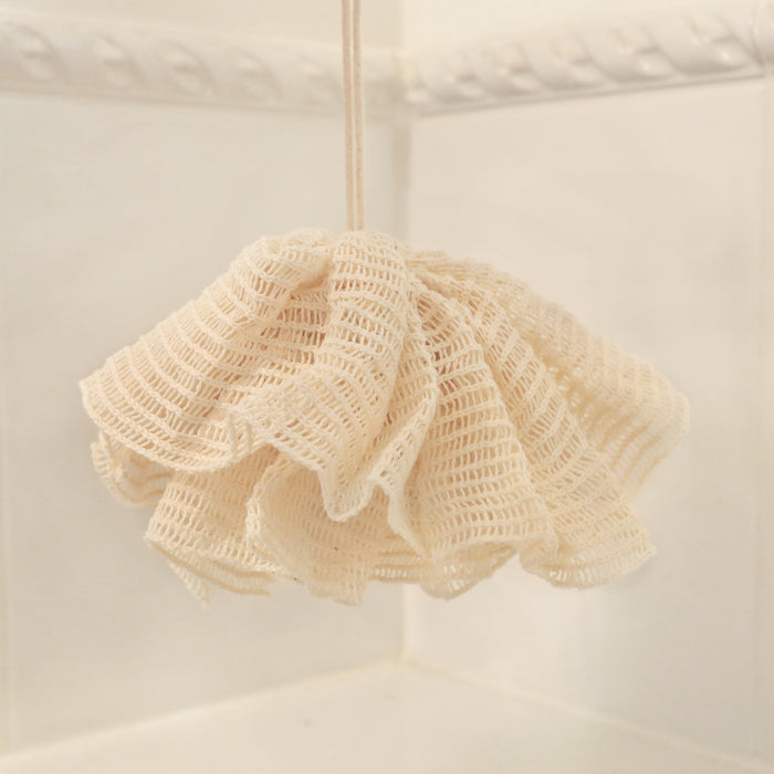 Natural ramie bath pompom hanging in the bathroom for body exfoliating.