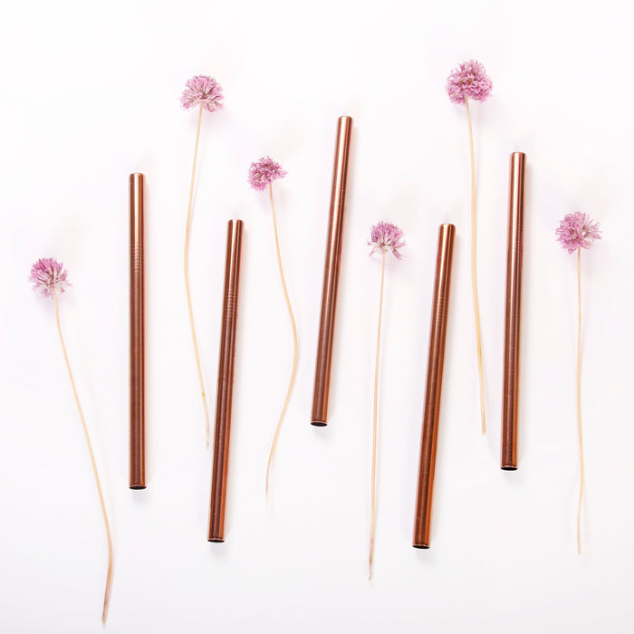 Rose gold stainless steel boba straws flat lay with chive blossoms.