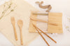 Eco Beige bamboo cutlery set with creamy color cotton fabric pouch and brown ribbon tapes attached. Set includes 6 pieces logo engraved cutleries ; spoon, fork, knife, chopstick, straw, and straw brush. White background with cotton mesh fabric and small white flowers..