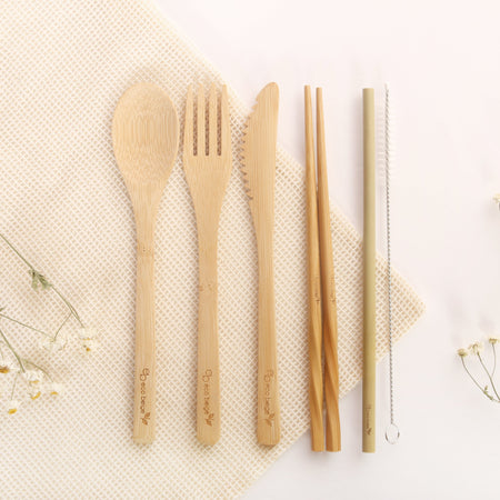 Eco Beige bamboo cutlery set includes 6 pieces logo engraved cutleries; spoon, fork, knife, chopstick, straw, and straw brush. White background with cotton mesh fabric layer and small white flowers.