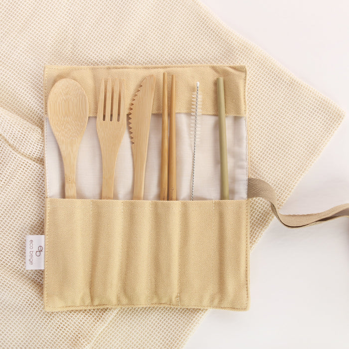Eco Beige bamboo cutlery set inside creamy color cotton fabric pouch, ready on the go. Set includes 6 pieces; spoon, fork, knife, chopstick, straw, and straw brush. Brown ribbon tapes attached to the pouch for wrap-up closure. White background with cotton mesh fabric layer.