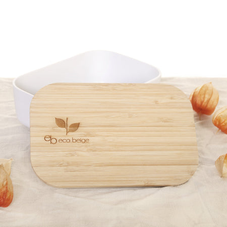 Eco Beige bamboo lunch box with engraved logo on the lid. Lunch box opened view with lid off. White container made with wheat fiber and bamboo fiber. White background with linen table cloth and red gooseberry flowers.