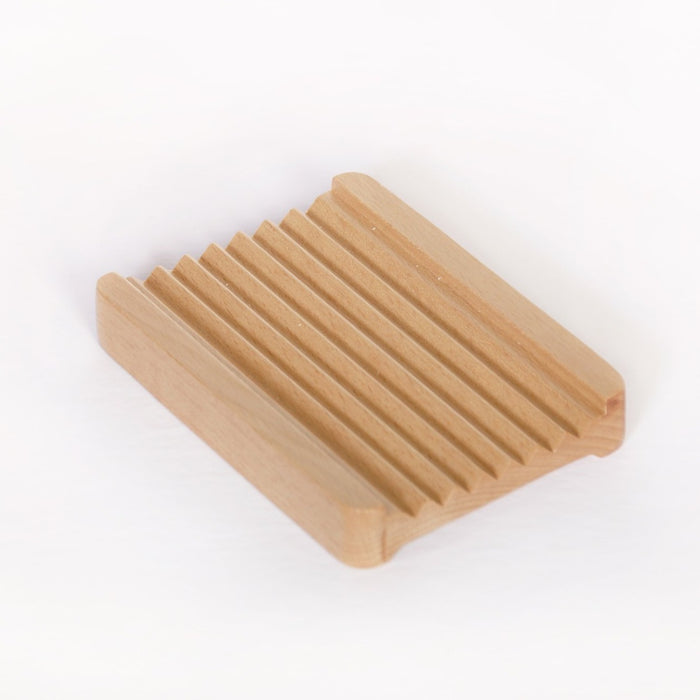Natural bamboo soap dish with white background. Features reversible sides, with ridged side facing up, and flat side facing down.