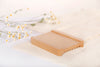 Natural bamboo soap dish with cotton mesh and white flower background. Features reversible sides, with flat side facing up, and ridged side facing down.