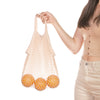 Eco Beige cotton netted hand bag with oranges inside. Held by model in beige color theme outfit and white background.