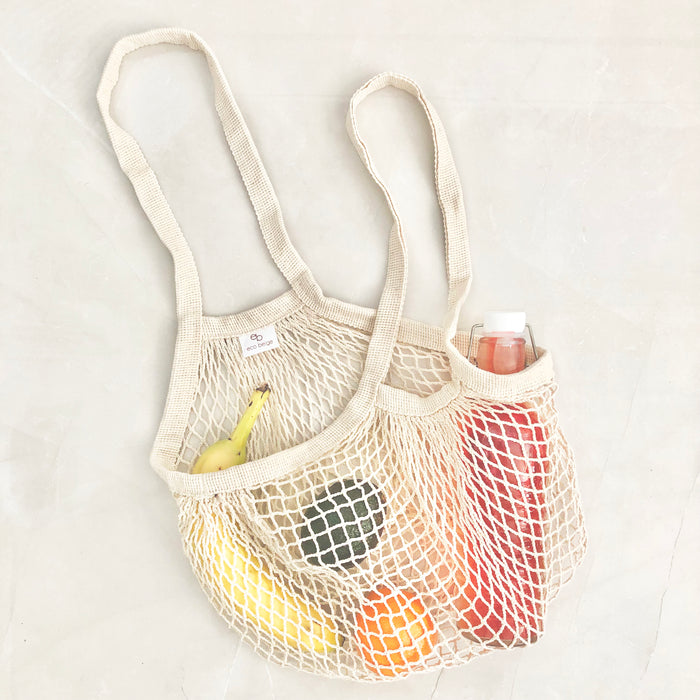 Eco Beige cotton netted shoulder bag flat layed with grocery inside, and light color stoned background.