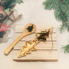 Gold Christmas Tree tea infuser opened with loose tea leaves inside and a bamboo teaspoon beside it. Holiday day season theme background