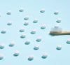 Huppy Natural toothpaste peppermint tablet spread across blue background. White tablet sitting on toothbrush
