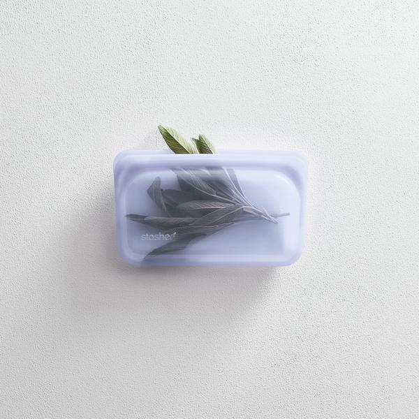 Stasher platinum silicone reusable lavender color snack bag storing sage herbs. In white background.