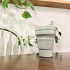 Sage color Stojo cup in 16oz. on the table with sage theme coordinate background..