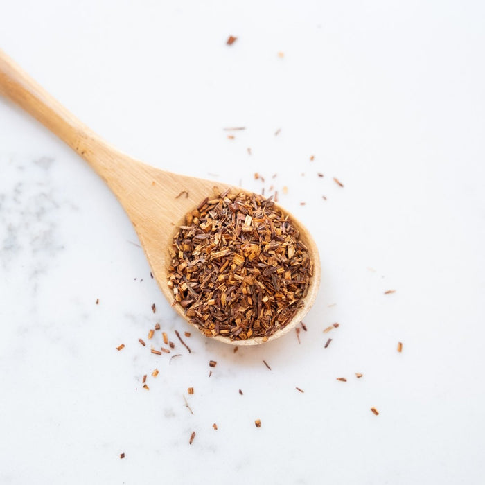 Rooibos Tea loose tea leaves on bamboo spoon.