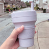 Lilac color Stojo cup in 16oz being held outdoor.