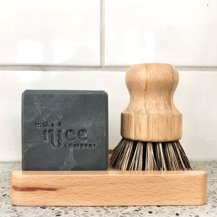 Kitchen sink with charcoal solid dish soap and natural bamboo coconut bristle scrub standing on the bamboo soap dish.