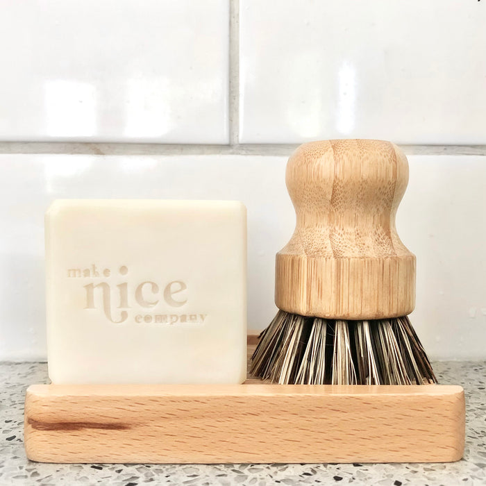 Kitchen sink with natural solid dish soap and natural bamboo coconut bristle scrub standing on the bamboo soap dish.